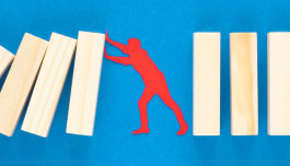 figura rossa con blocchi di legno e sfondo azzurro 